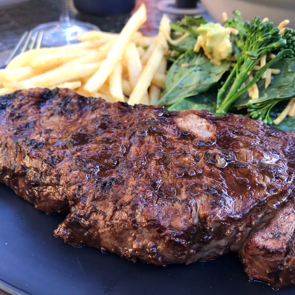 Jerk marinaded steak and fries with broccolini salad